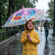 Girl in a yellow raincoat holding a pink tropical umbrella with stitch and palm leaves