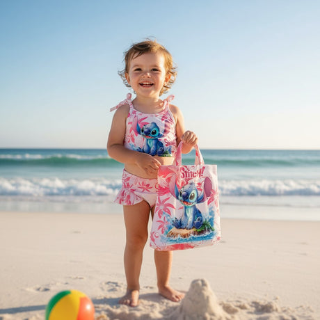 Child in a swimsuit holding a Lilo & Stitch bag on a beach