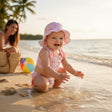 Baby wearing a pink striped bow swimsuit with a matching bucket hat