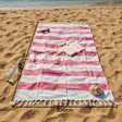 Pink and white striped beach towel on a sandy beach with measurements indicated.