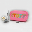 Pink pouch with 'STUFF' text, hair clip, and flower on a light grey background