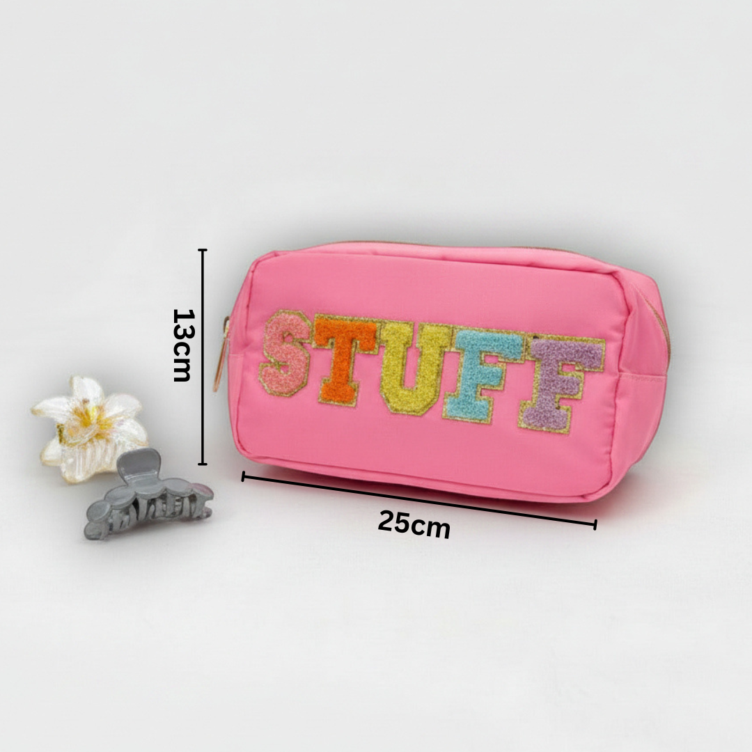 Pink pouch with 'STUFF' text, hair clip, and flower on a light grey background