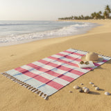 Checkered beach towel on sand with ocean and palm trees in the background