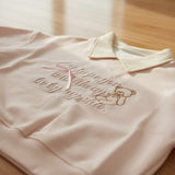 Close view of the tonal teddy bear embroidery and satin ribbon bow on pink fleece