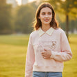 Pink teddy bear sweatshirt styled with jeans in a park at golden hour