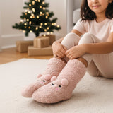 Child wearing pink fuzzy slippers with a Christmas tree and presents in the background