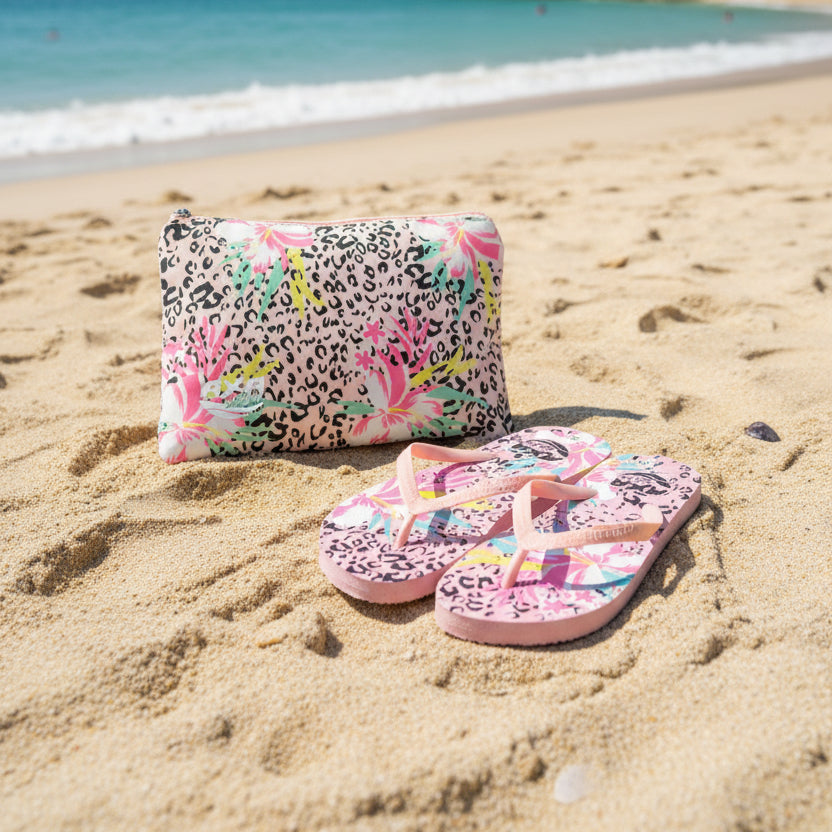Flip flops and pouch with floral and leopard print design on sand