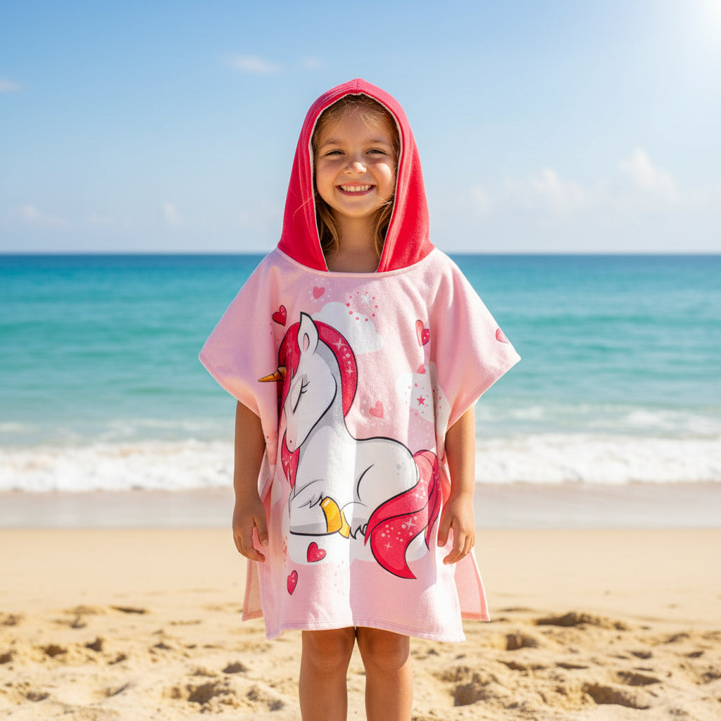 Pink hooded poncho with unicorn design on a the beach