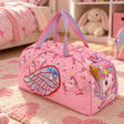Pink unicorn print duffle bag with a holographic wing and gold horn on a heart rug in a girls bedroom