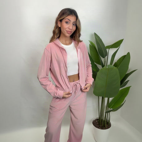 Woman in a pink velour zip hoodie worn open over a white crop top with matching pants