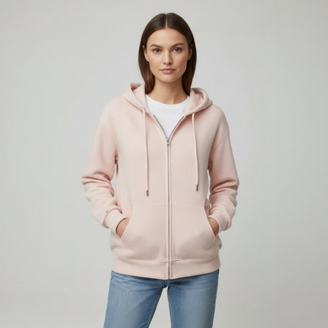 Woman wearing a light pink hoodie and blue jeans on a plain background