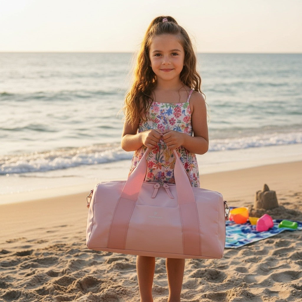 Young girl holding a pink beach bag on a sandy beach with ocean in the background