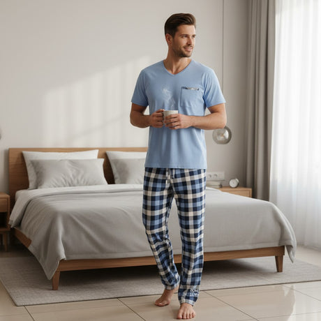 Plaid pyjama set worn holding a mug beside a neatly made bed