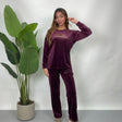 Woman in a plum velvet PJ set with Enjoy The Journey gold print top and straight pants