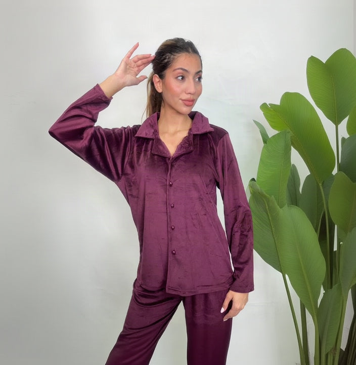 Woman in a plum velvet button up PJ set posing with a hand in her hair