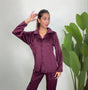 Woman in a plum velvet button up PJ set posing with a hand in her hair