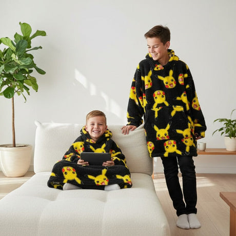 Two kids in black Pikachu print hooded blankets on a sofa