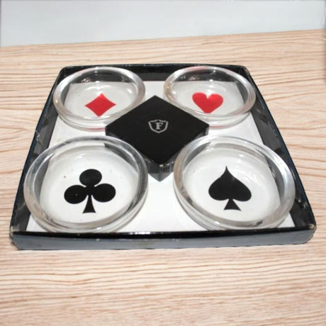 Four glass ashtrays with playing card suits on a wooden surface