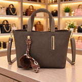 Grey brown tote with stitched handles, gold bars and a brown chain print scarf with a pom pom