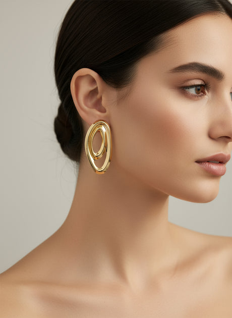 Woman wearing gold hoop-shaped earrings against a neutral background