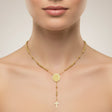 Gold necklace with a round pendant and cross on a neutral background