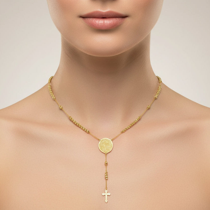 Gold necklace with a round pendant and cross on a neutral background