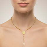 Gold necklace with a round pendant and cross on a neutral background