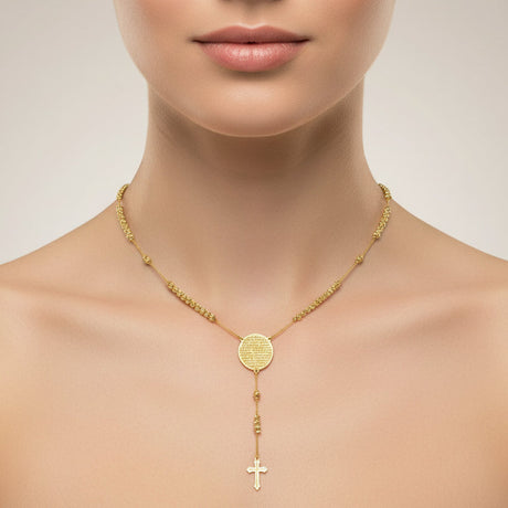 Gold necklace with a round pendant and cross on a neutral background