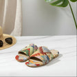 Colorful patterned handmade slippers on a white surface with a hat and sunglasses in the background