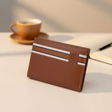 Brown leather wallet with striped design on a table with a cup of coffee in the background