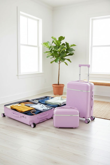 Purple suitcase packed open with clothes beside a cabin case and vanity case