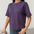 Person wearing a purple tshirt and blue jeans against a plain background