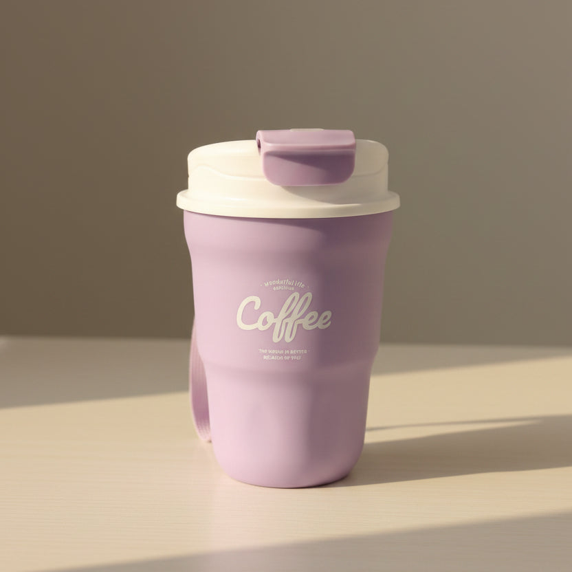 Purple coffee tumbler with white text on a white surface, with stacks of folded clothes in the background.