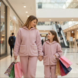 Mother and daughter in matching mauve fleece hoodie sets carrying shopping bags