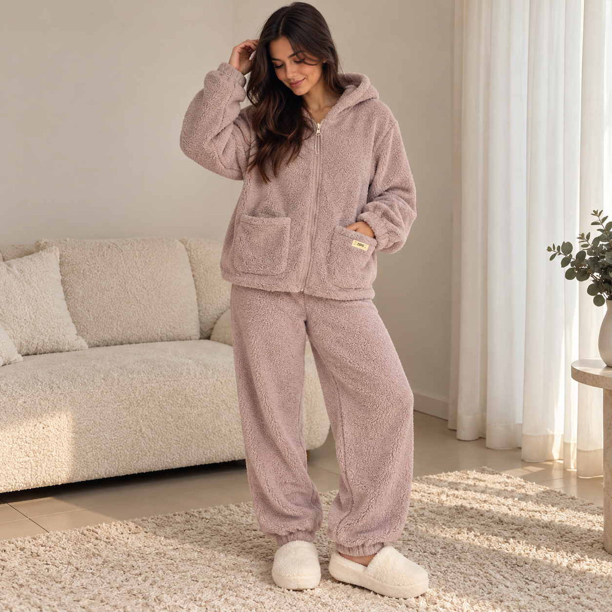 Woman in a mauve purple teddy fleece zip hoodie and joggers with the hood on, relaxing at home