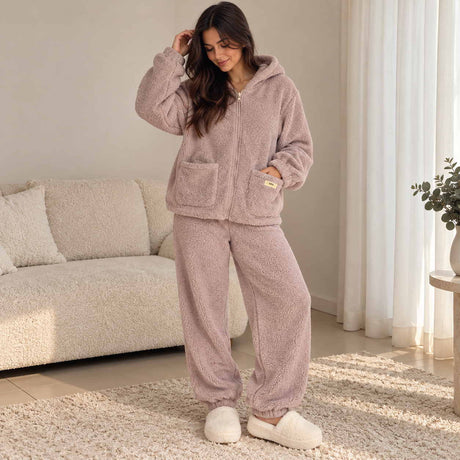 Woman in a mauve purple teddy fleece zip hoodie and joggers with the hood on, relaxing at home