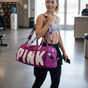 Woman holding a berry purple gym duffel bag indoors