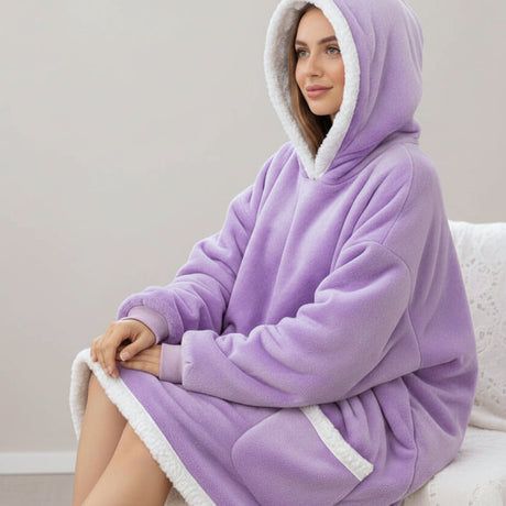 Person wearing a purple hooded blanket with white trim sitting on a white chair.