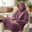 Curled in a boucle armchair, hood raised, in a dusty mauve blanket with an ivory sherpa lining