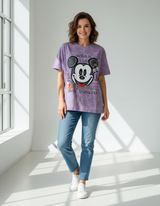 Woman wearing a purple tshirt with a cartoon character design in a bright room