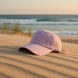 Lavender cotton summer cap on sand dunes at sunset with waves behind