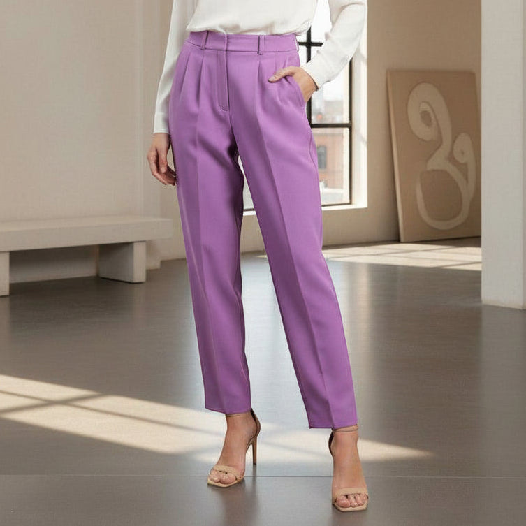 Person wearing purple pants and a white top in a room with a neutral color scheme