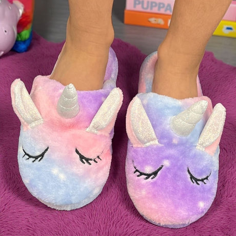 Purple and pink tie dye unicorn slippers with white glitter ears on a magenta throw