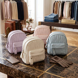 Lilac, cream, pink and blue quilted mini backpacks on a marble counter