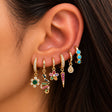 Ear stacked with gold huggies with an emerald flower, rainbow snake, petal flower, red spike and turquoise hoop