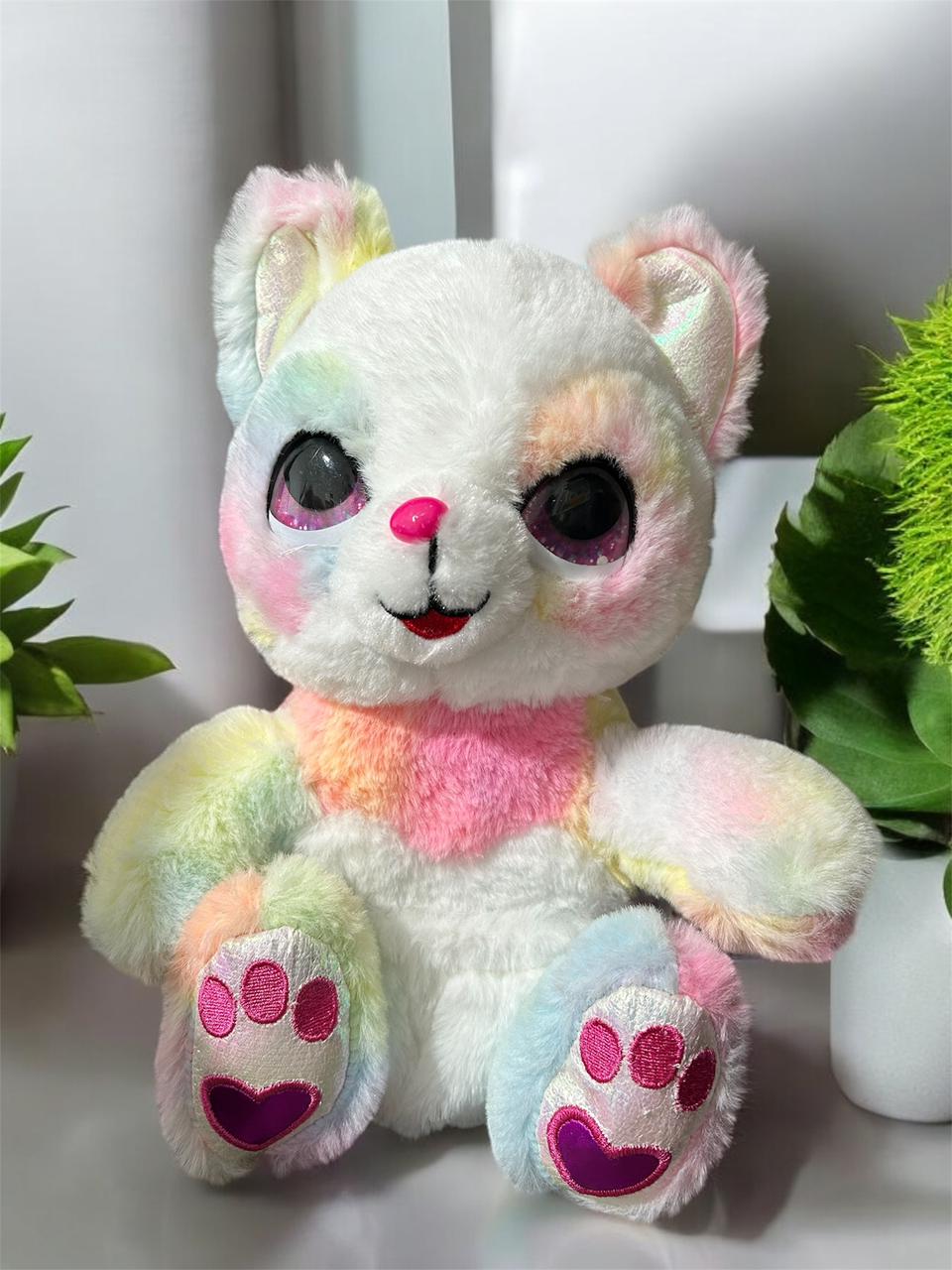 Seated long pile plush in pastel rainbow tie dye with glittery eyes and a heart nose