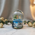 Snow globe with the Raouche Pigeon Rocks in a blue sea, on a sculpted Beirut skyline base