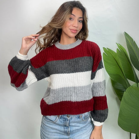 Closer view of a red and grey striped knit sweater with ribbed white cuffs and grey neckline