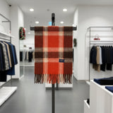 Red plaid scarf on a clothing rack in a store setting