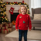 Toddler in a red Christmas patch sweater standing in a decorated living room